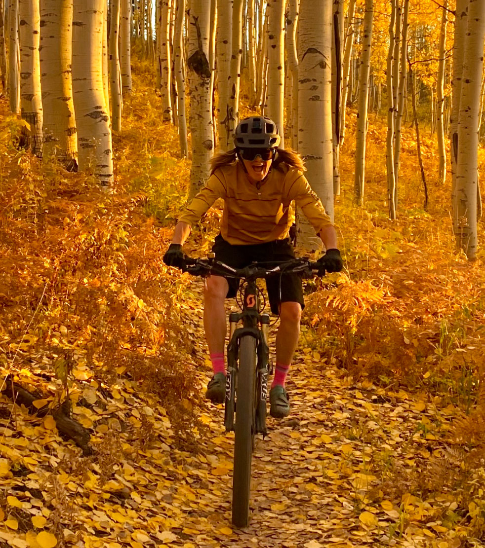 Woman riding bike in golden fall leaves