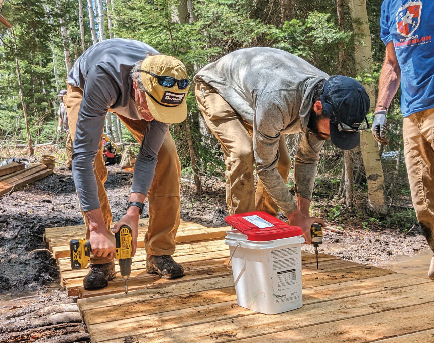 People building a wooden bridge for a bike trail